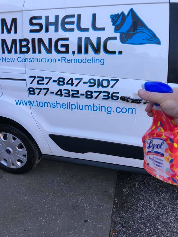 A Hand Holding a Lysol in Front of a Plumbing Van